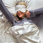 woman wearing a sleep mask and pajamas, lying in bamboo sleeping bag liner.