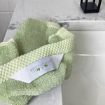 hang tag showing with BedVoyage logo on a sage green washcloth on sink