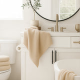 Bathroom with beige towel on sink and round mirror above.