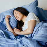 woman sleeping in bed with her head laying on ocean blue bamboo pillows with bamboo sheets