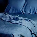dark indigo blue quilted bamboo coverlet and sheets on an elegant bed
