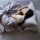woman sleeping in silver gray platinum bamboo bed sheets made on a bed with pillows