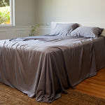 silver gray platinum bamboo bed sheets made on a bed with pillows and woven rug on floor