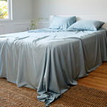 sky blue bamboo bed sheets and pillows in a bedroom with woven rug
