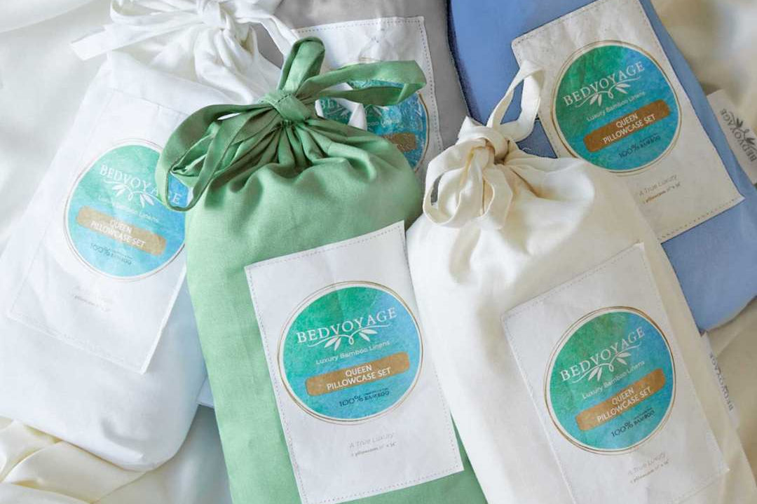 Set of drawstring bamboo pillowcase bags with visible branding on a white fabric background