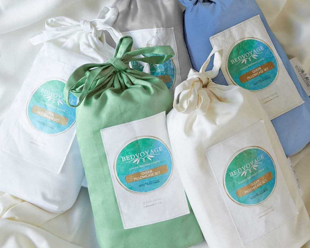 Set of drawstring bamboo pillowcase bags with visible branding on a white fabric background