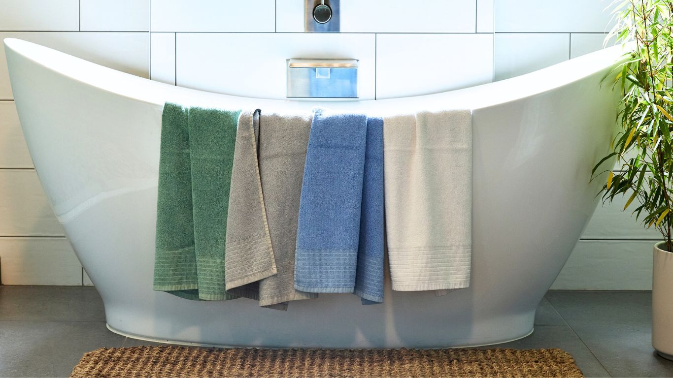 Colorful bamboo towels hanging over a white bathtub in a bathroom setting.
