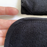 closeup image of a black bamboo facial washcloth in womans hand