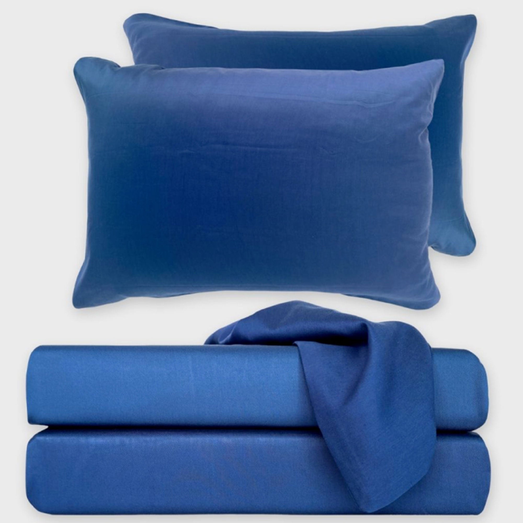 dark blue indigo bamboo sheet set stack with floating pillows and draped pillowcase