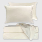 ivory bamboo sheet set stack with floating pillow and draped fabric