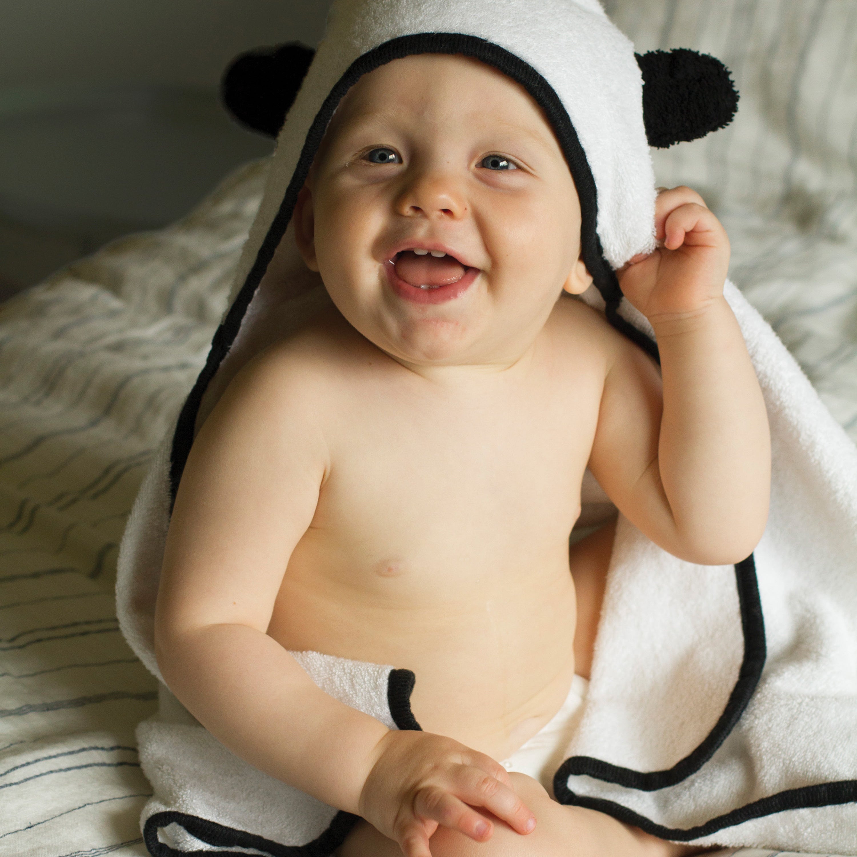 baby boy laughing while wrapped in hooded baby bamboo towel with panda ears