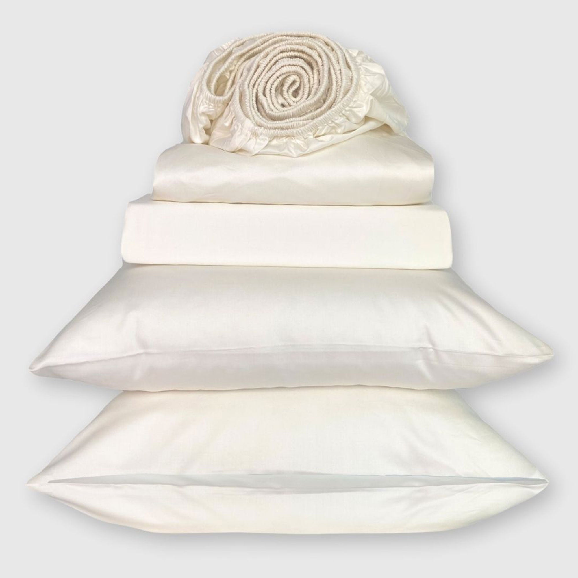 ivory bamboo bed sheet stack with fitted sheet on top rolled into a jelly roll shape
