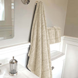 sand beige melange bamboo bath sheet and hand towel set hanging in a bathroom