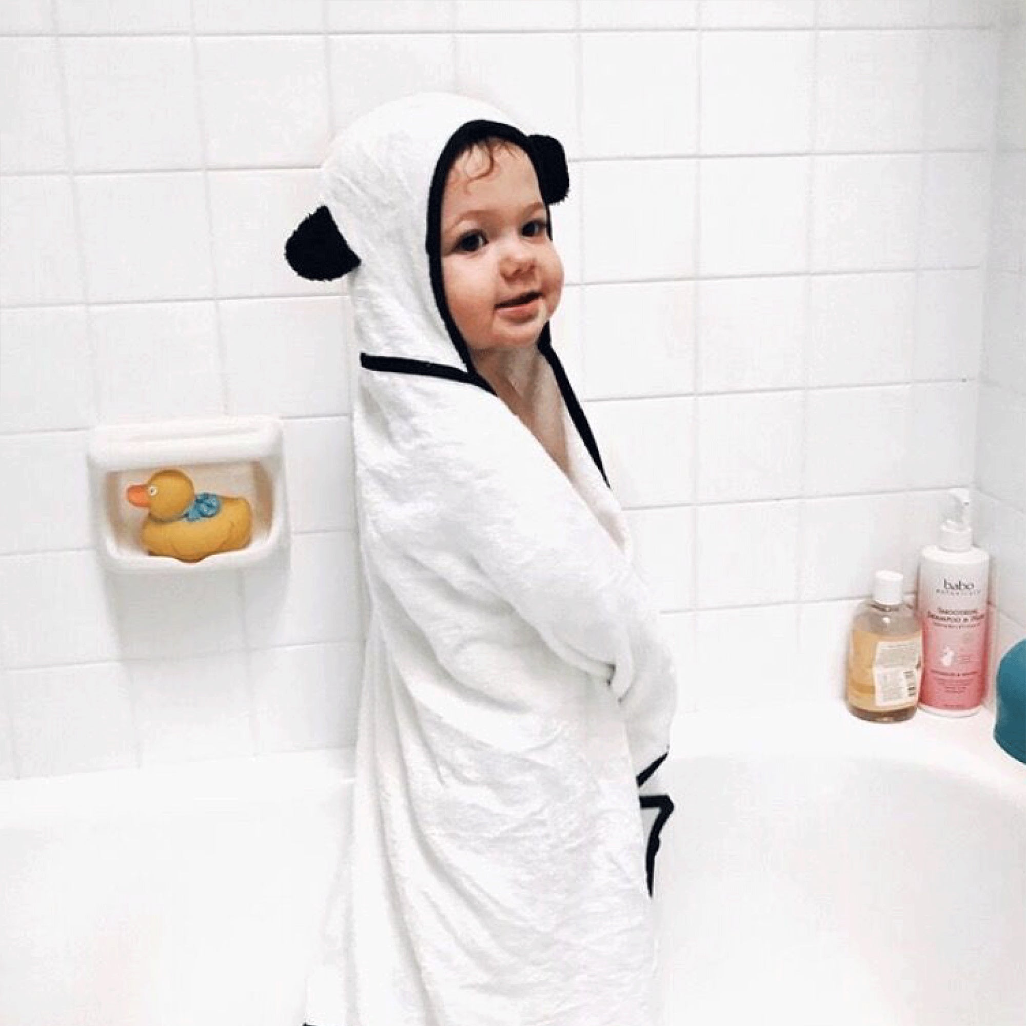 toddler boy standing in tub with bamboo hooded towel wrapped around him