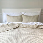 bed image with sand beige bamboo melange quilted coverlet and standard shams with brick pattern