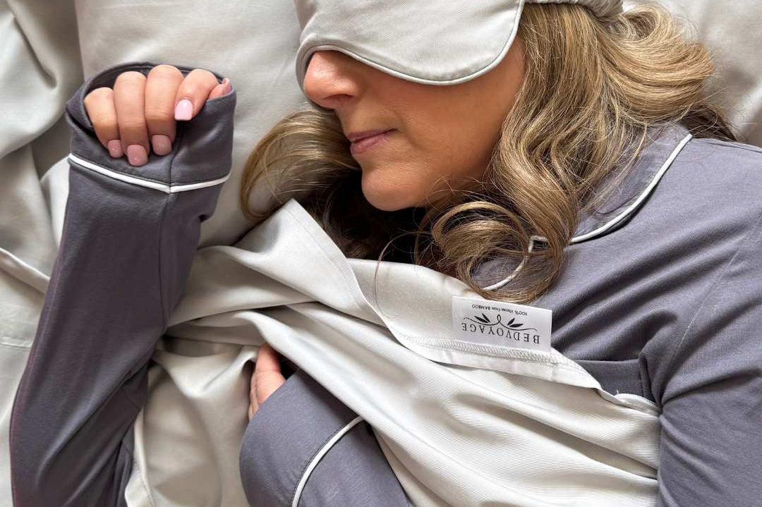 blond woman wearing a sleep mask and pajama set in a bamboo sleeping bag liner