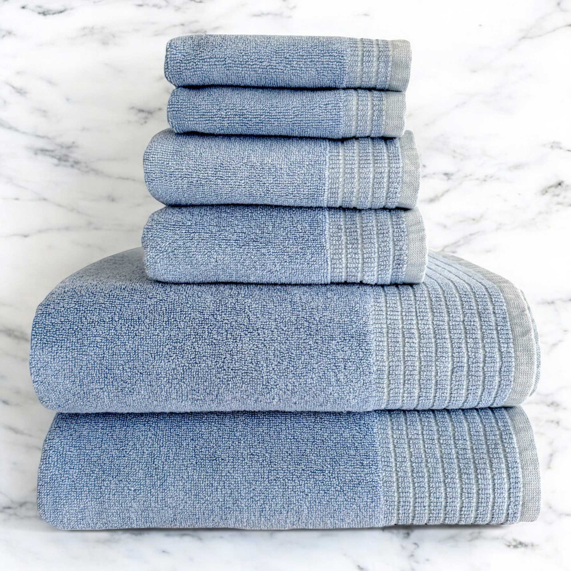 A set of ocean blue colored bamboo spa towels neatly stacked, including bath towels, hand towels, and washcloths.