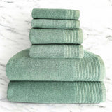 A set of folded green bamboo and cotton spa towels on a marble surface.
