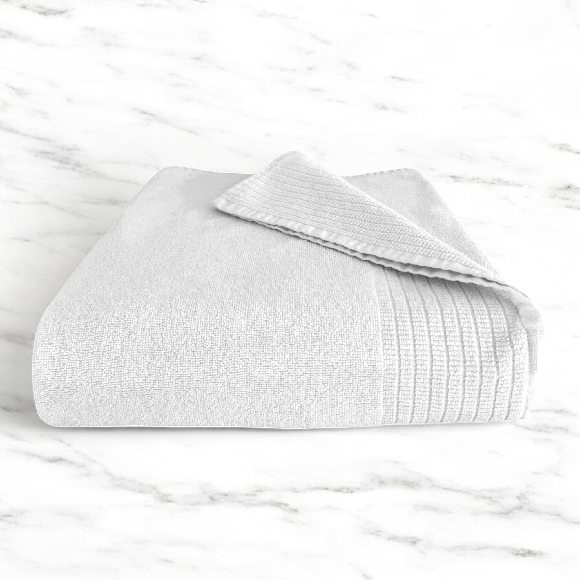 white folded bamboo bath towel sitting on a marble countertop