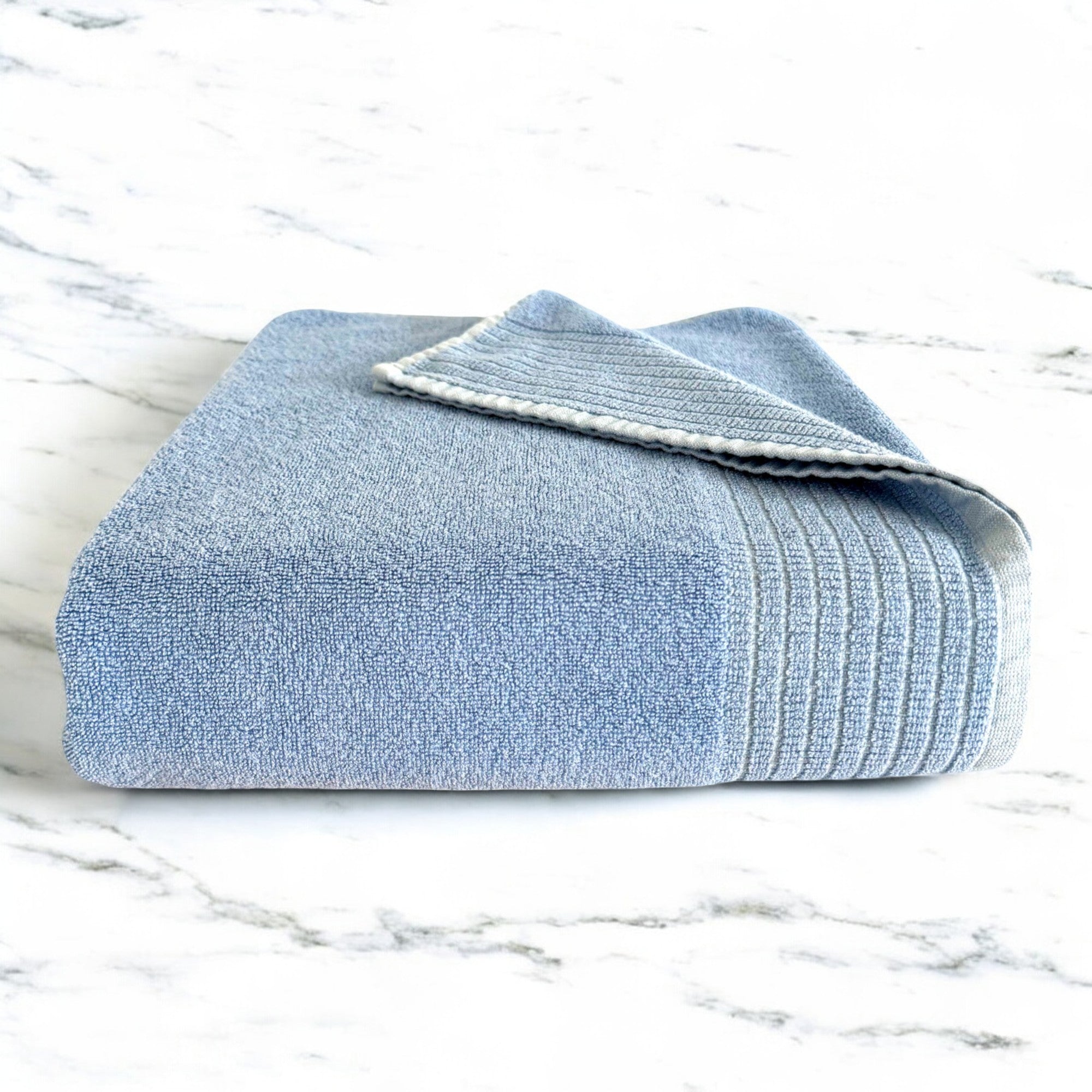 ocean blue folded bamboo bath towel sitting on a marble countertop