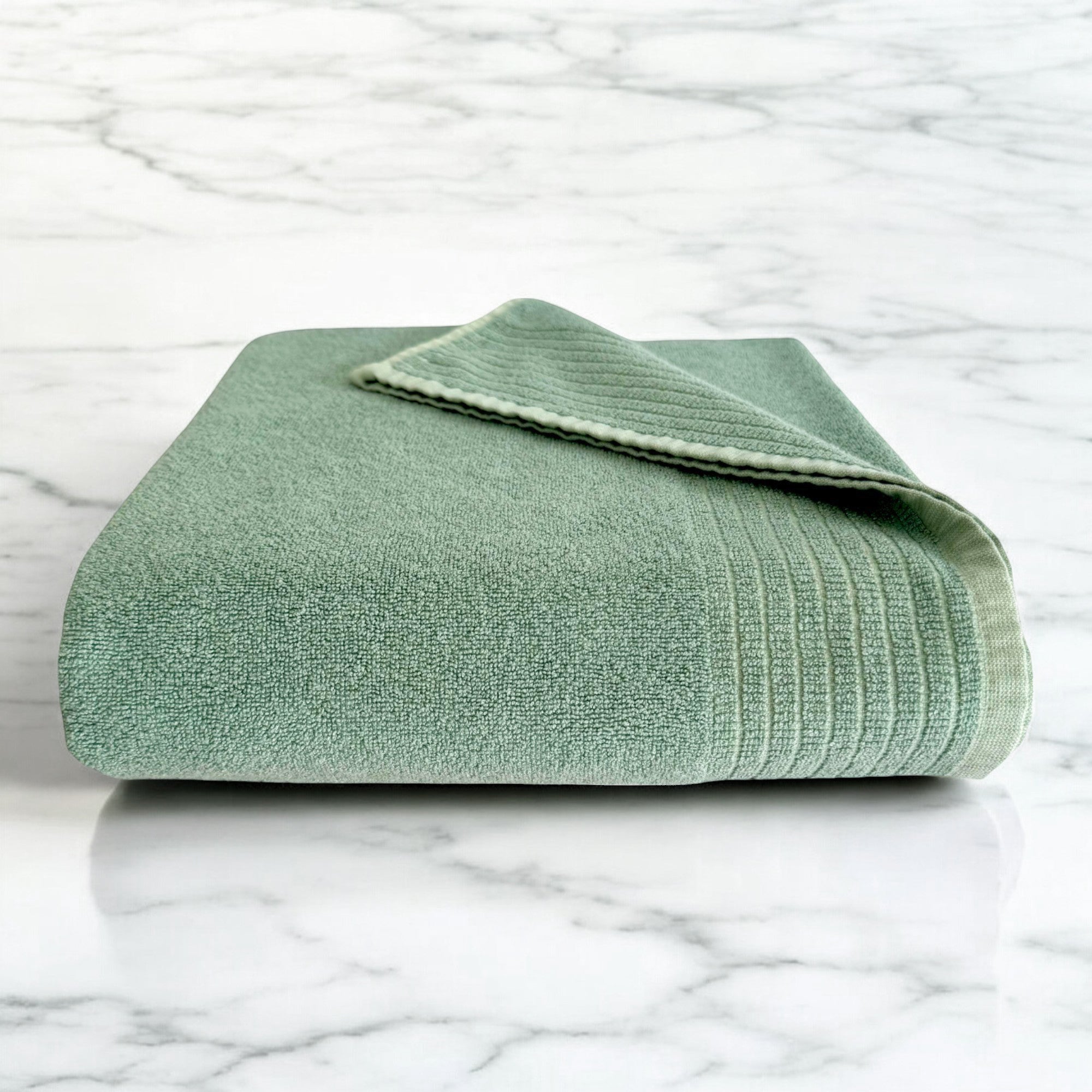 seaglass green folded bamboo bath towel sitting on a marble countertop