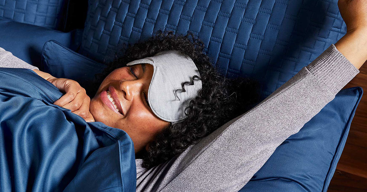 Woman with sleep mask stretching in bed