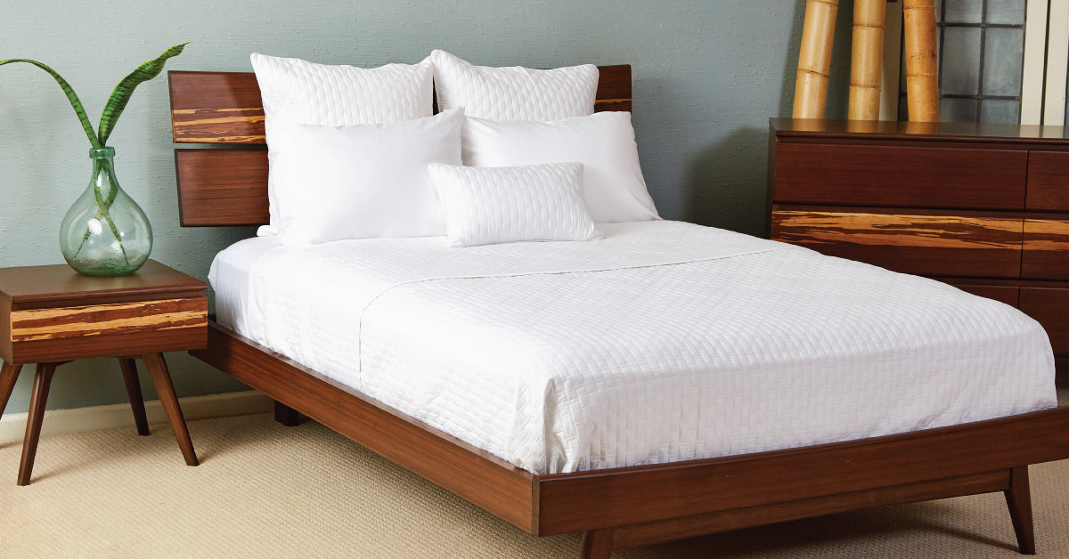 Bed with white sheets and wooden nightstand 