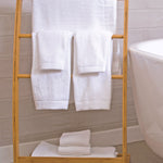 8pc White bamboo towels hanging on a bamboo rack in a bathroom