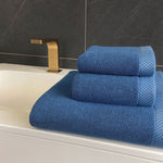Blue towels on a bathroom sink with a gold faucet.