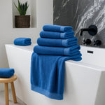 Stack of blue towels on a white bathtub in a bathroom setting