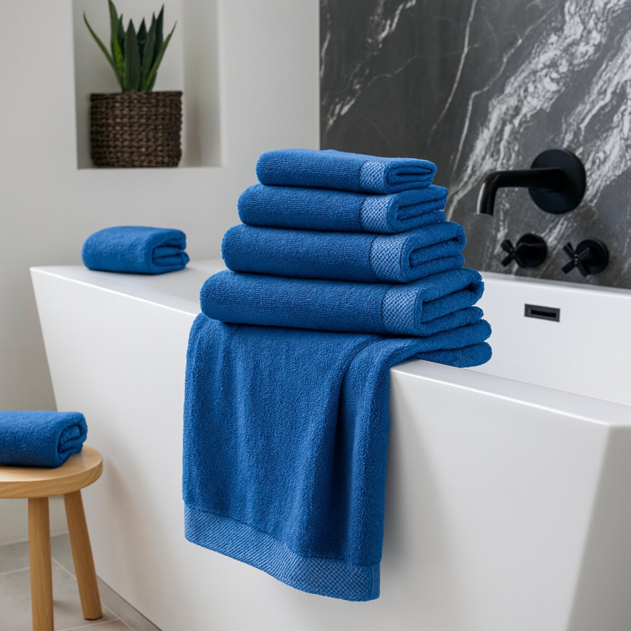 Stack of blue towels on a white bathtub in a bathroom setting