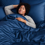 woman sleeping in bed with dark blue bamboo duvet cover and shams