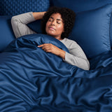 woman sleeping in bed with dark blue bamboo duvet cover and shams