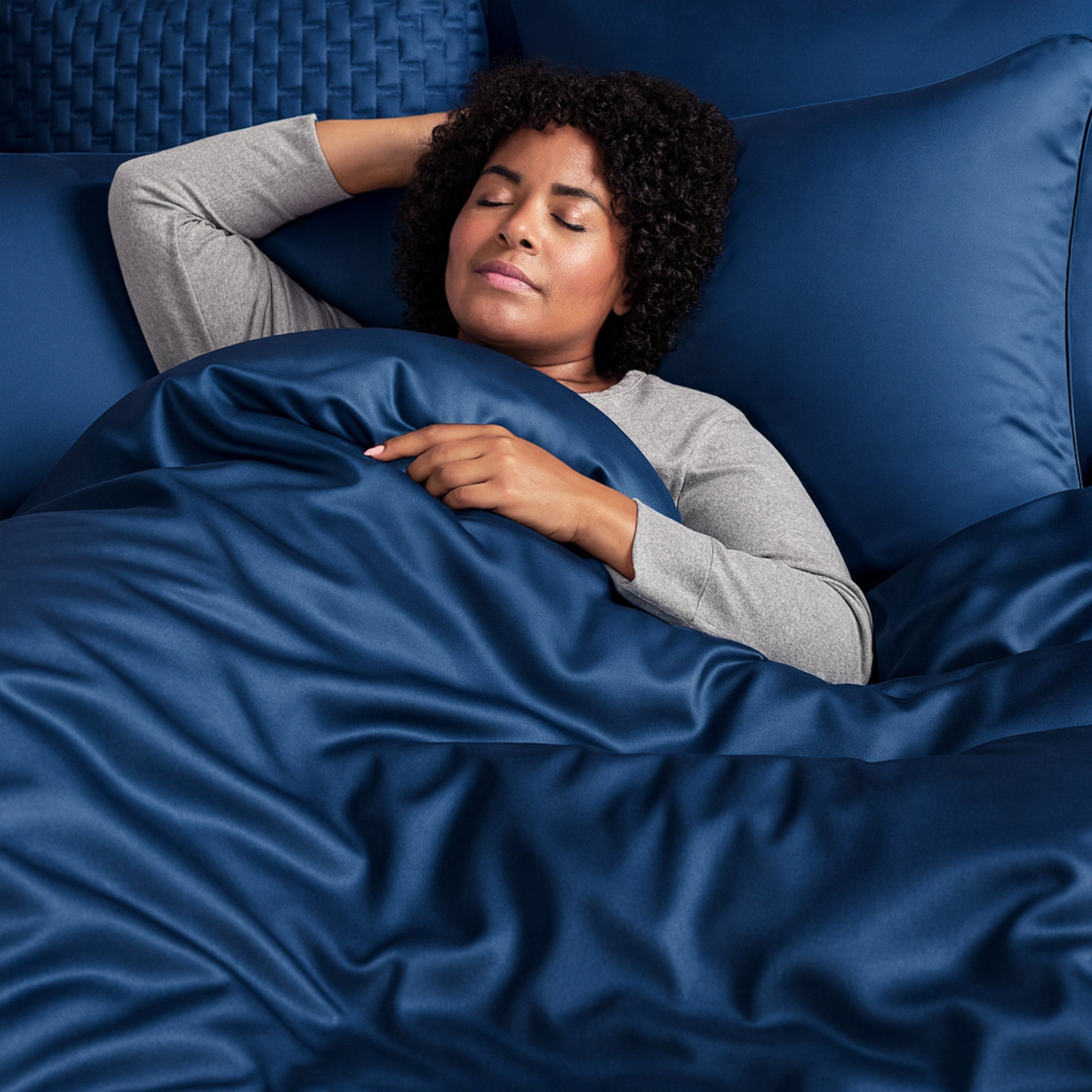 woman sleeping in bed with dark blue bamboo duvet cover and shams
