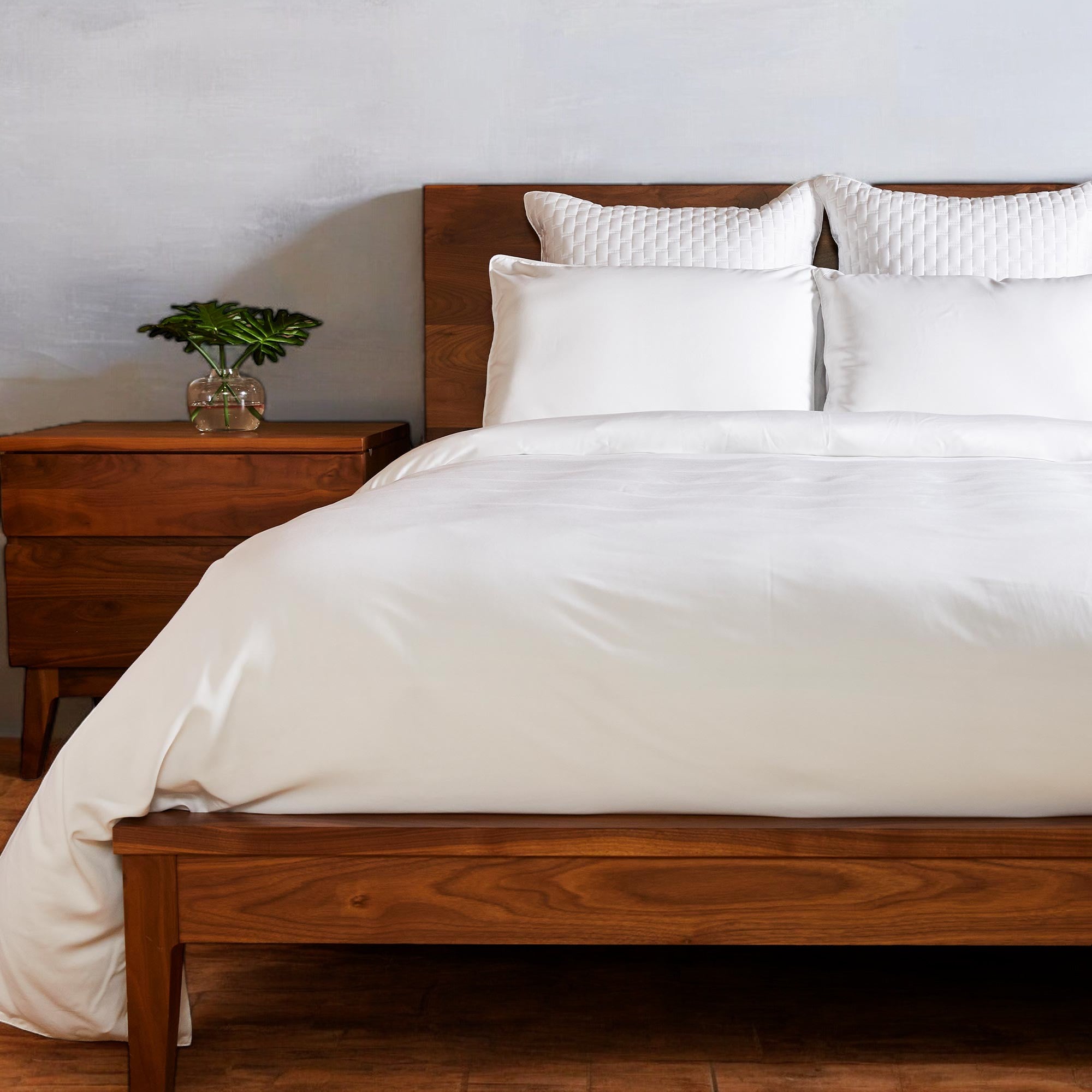 white bamboo duvet cover on a wood frame bed with plant on nightstand