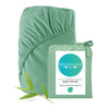 Green bamboo fitted sheet with packaging and leaf on a white background