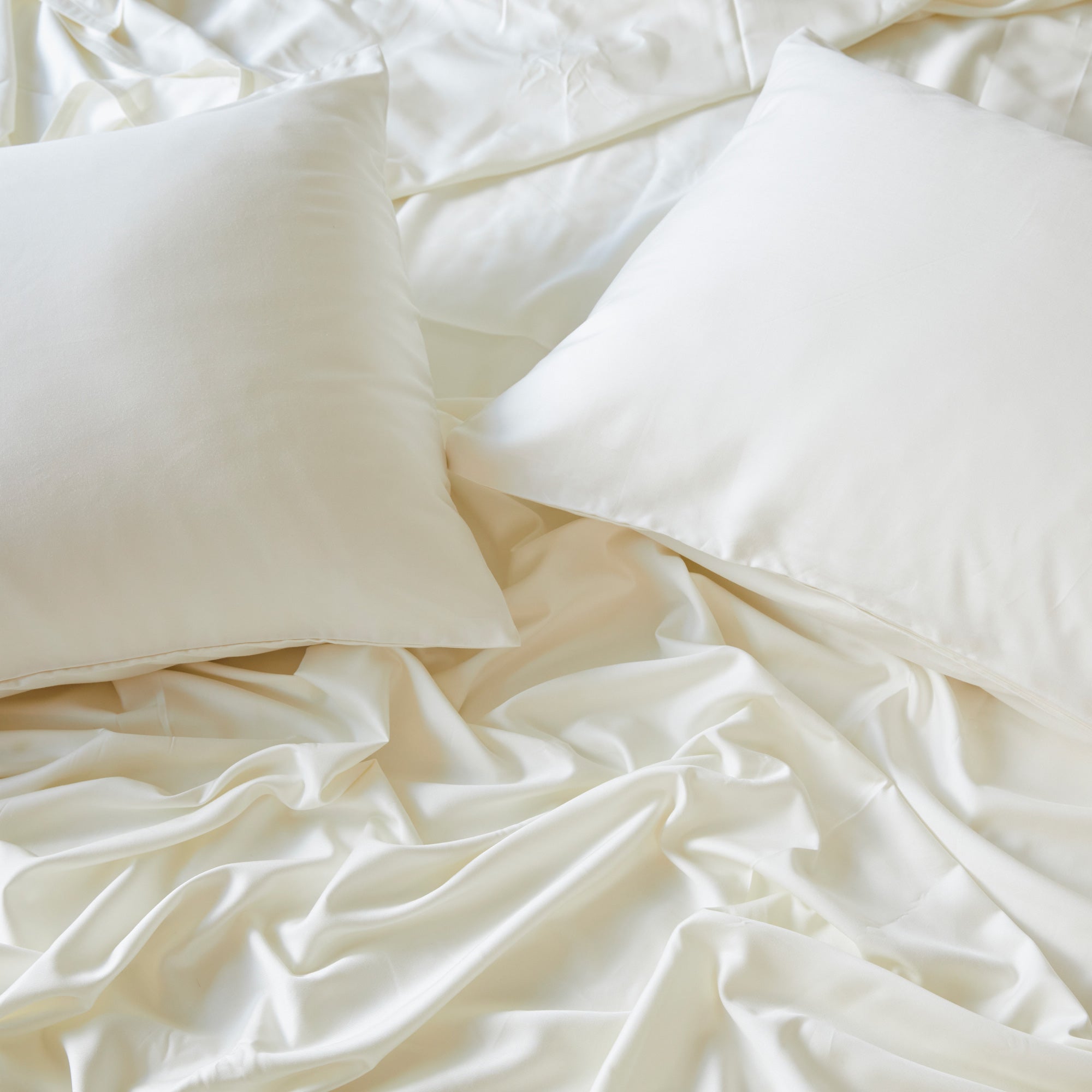 2 ivory bamboo pillowcases on pillows with a flat sheet in an elegant bed