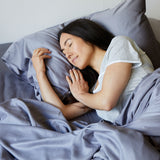 dark haired lady sleeping in gray bamboo sheets with her head on pillow