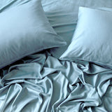 2 sky blue pillows and a flat sheet on an elegant and messy bed 