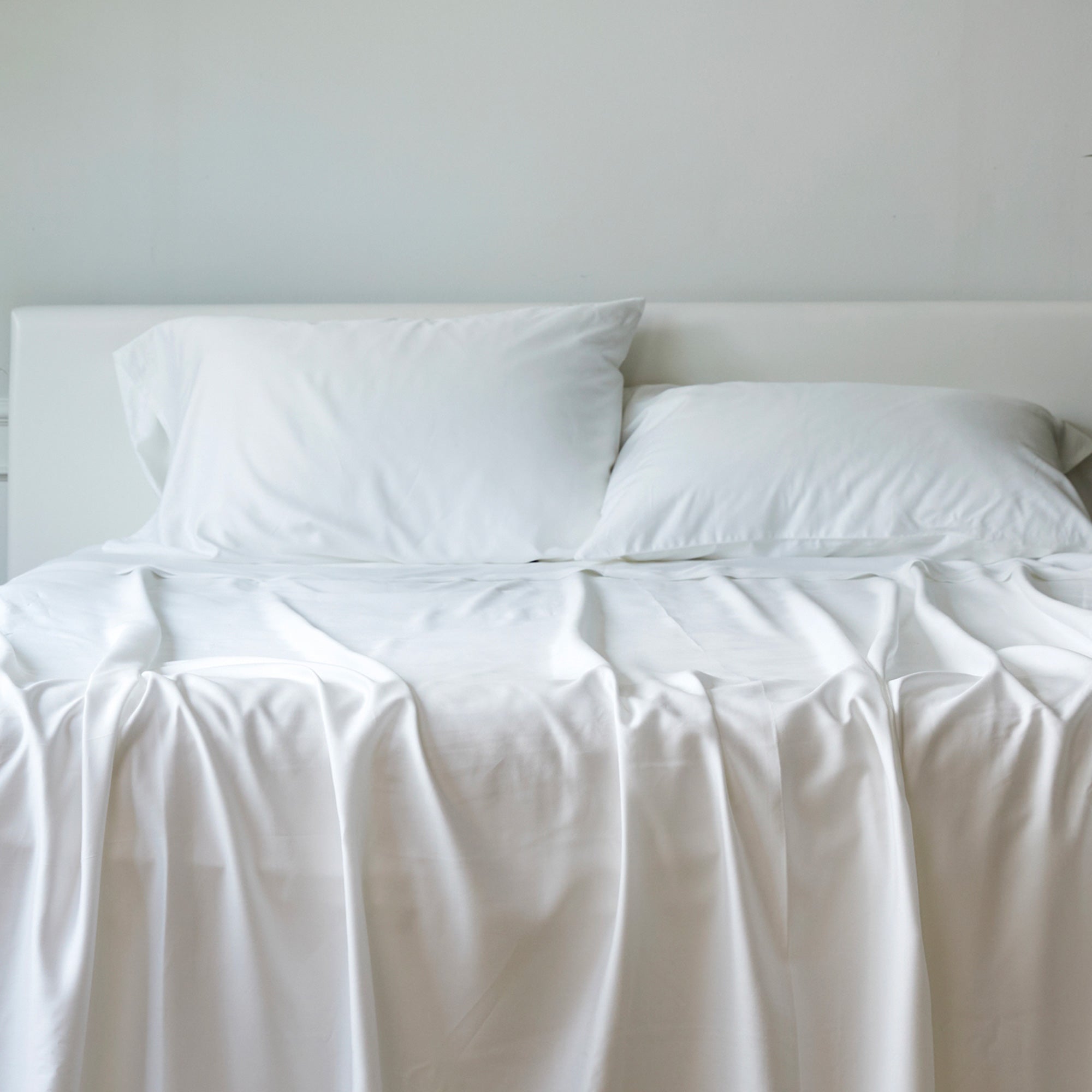 White bed with two pillows on a plain background