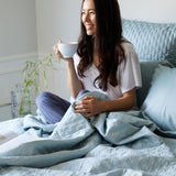 light blue sky bamboo quilted coverlet and lady drinking coffee in bed