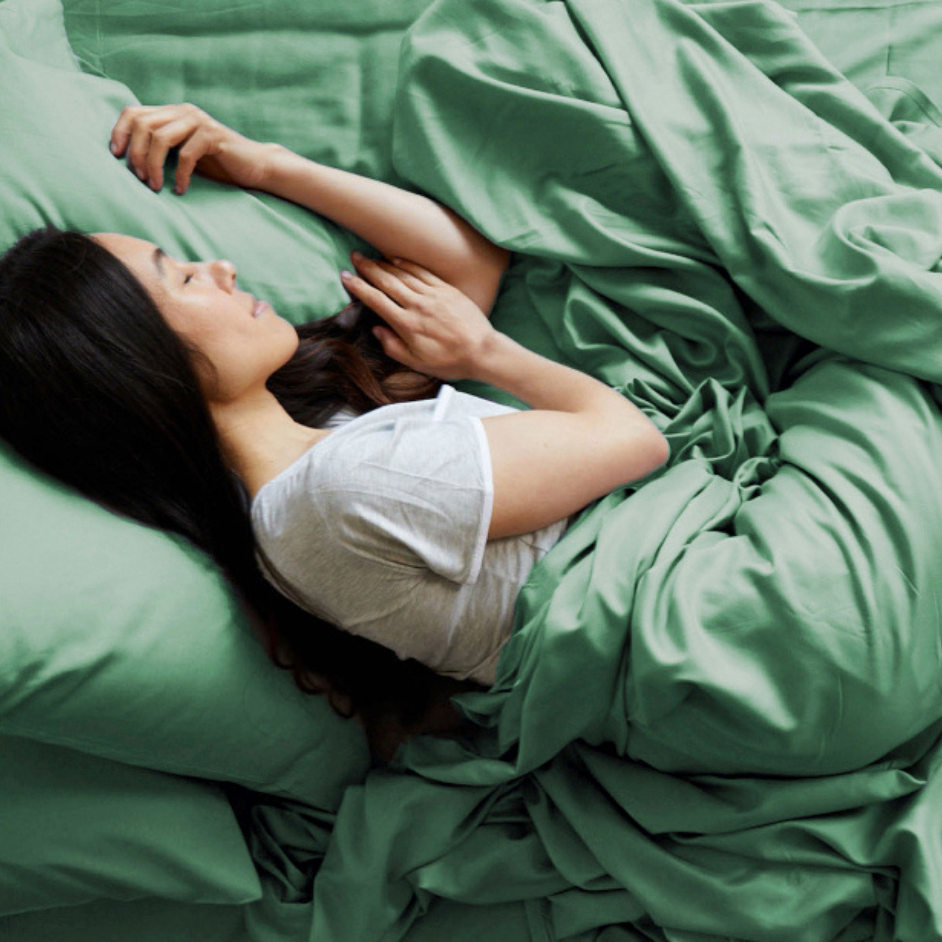 Woman lying in bed with green bamboo bedding