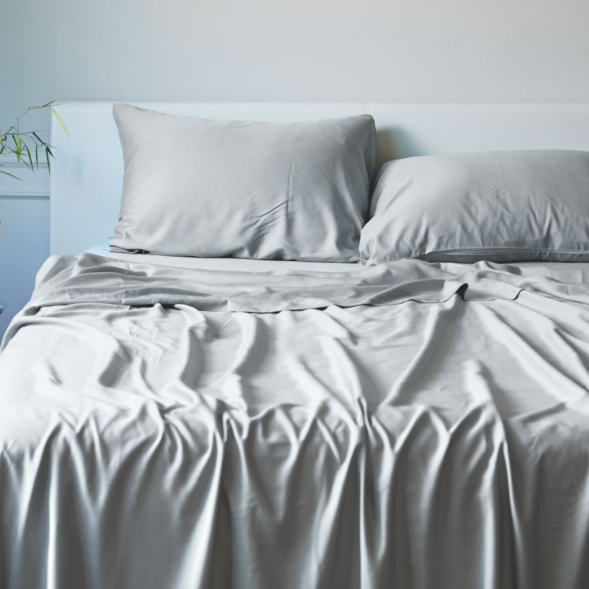 light gray bamboo bed sheets draped over a bed with pillows