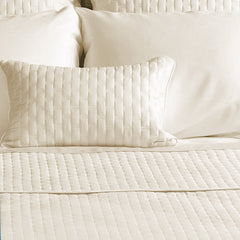 ivory quilted bamboo decorative pillow on a bed with coverlet 