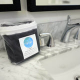packaged 6 pack of luxury black bamboo facial washcloths on bathroom counter