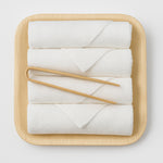 White fingertip towels on a wooden tray with wooden handles on a light gray background