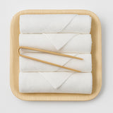 White fingertip towels on a wooden tray with wooden handles on a light gray background