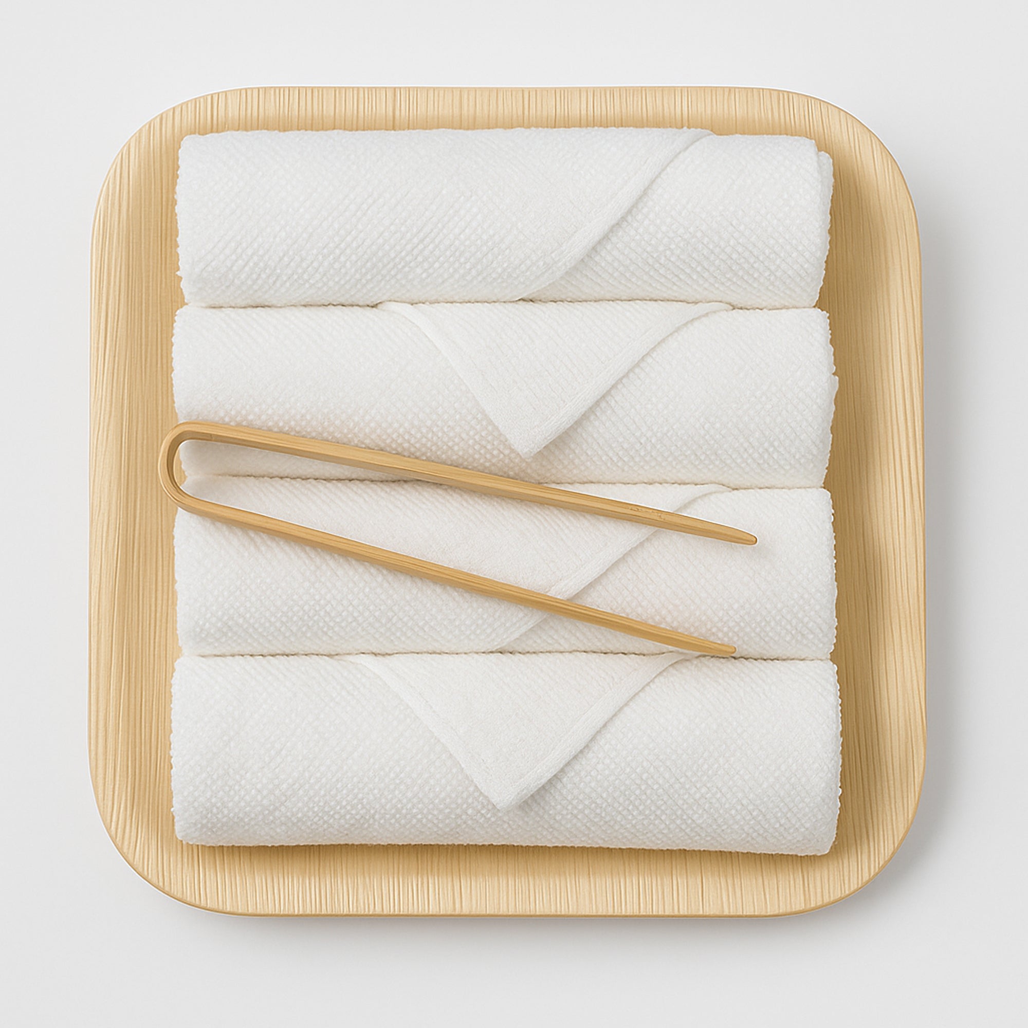 White fingertip towels on a wooden tray with wooden handles on a light gray background