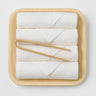 White fingertip towels on a wooden tray with wooden handles on a light gray background