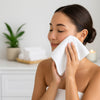 Woman cleaning her face with a white towel in a serene setting